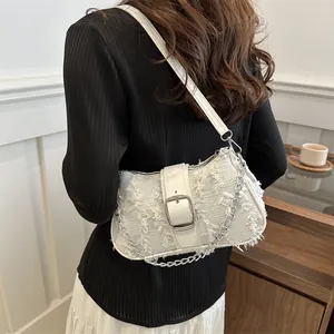 White tweed shoulder bag featuring a silver buckle and chain, worn by a model