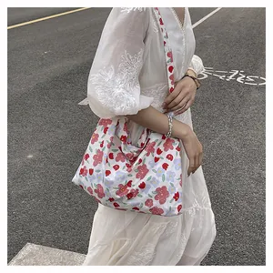 Detailed view of floral canvas tote bag with red and blue patterns on white dress