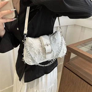 Close-up of white tweed shoulder bag featuring a leather buckle and silver chain strap