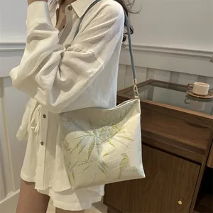 Detail of embroidered bamboo leaves and birds on premium beige jacquard fabric bag
