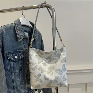 Close-up of golden butterfly embroidery and metal hardware on cream shoulder bag