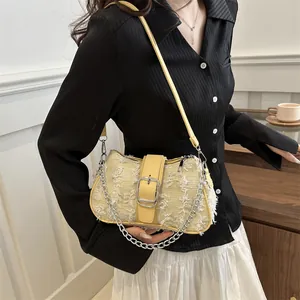 Detail of beige tweed underarm bag featuring a yellow leather strap and silver metal buckle