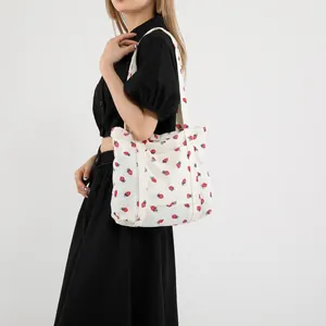 Macro detail of beige corduroy tote bag featuring an all-over red strawberry print pattern