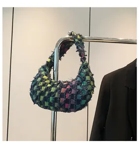 Detail of tweed checkered hobo bag with frayed edges hanging on a metal display stand