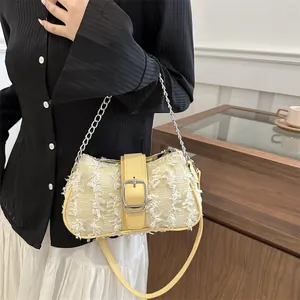 Detail of beige tweed handbag with white fringe trim and silver buckle on a strap