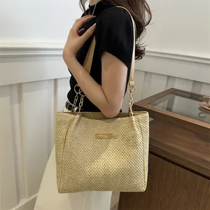 Detalle del bolso tote beige trenzado con etiqueta de cuero FASHION y cadena metálica