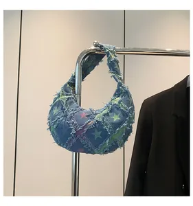 Detail of crescent denim hobo bag with frayed edges and colorful star print