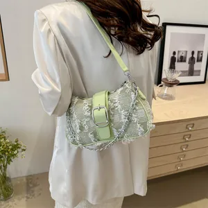 Detail of light green tweed underarm bag with fringe edges and metallic chain strap
