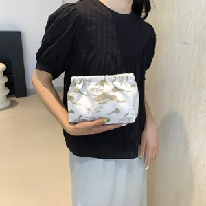 Détail du sac nuage blanc avec imprimés de paysages verts et fermeture plissée