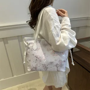 Sac fourre-tout chic avec imprimé papillon rose et cordons latéraux porté par un mannequin