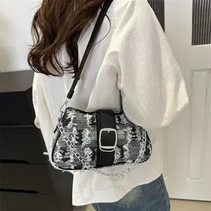 Detail of tweed underarm bag with belt buckle and chain strap shown on a model