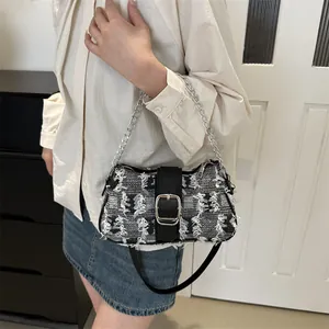 Close-up of woven black and white texture with silver buckle and metal chain strap