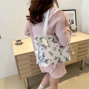 Détail du sac cabas blanc avec imprimé papillon et finitions latérales à cordon