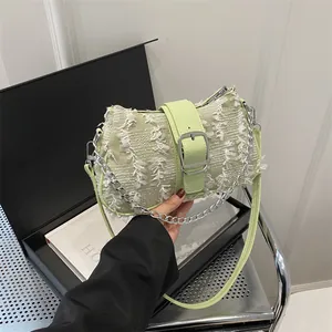Detail of light green tweed shoulder bag featuring white fringe and silver buckle closure