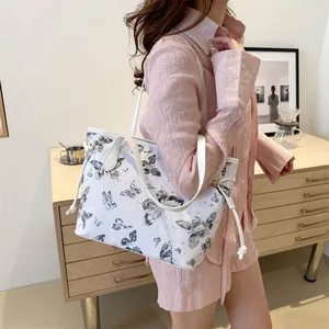 Gros plan d'un cabas blanc avec imprimés papillons porté avec une chemise rose texturée