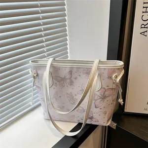 Détail du sac cabas blanc avec motifs papillons roses et accents de bagues en métal