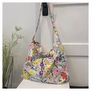Detail of floral canvas tote bag showing colorful flower patterns and wide shoulder strap
