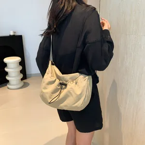 Detail of khaki drawstring crossbody bag in waterproof nylon with black adjustable strap