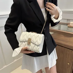 Vue détaillée de la texture matelassée blanc crème et de la chaîne dorée de ce sac élégant