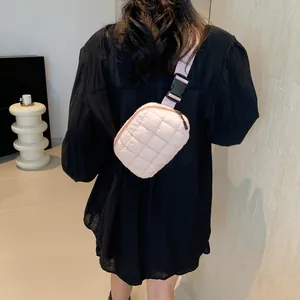 Détail du sac banane matelassé rose porté par un mannequin sur une robe noire