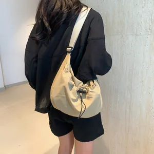 Close-up of khaki drawstring crossbody bag with wide strap on model for a casual look