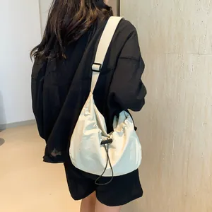 Chic off-white crescent crossbody bag with drawstring details and wide shoulder strap