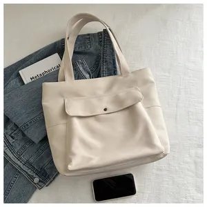 Détail du sac fourre-tout en toile crème avec poche avant à rabat et bandoulières robustes