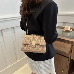 Détail du sac matelassé plissé beige avec chaîne dorée et fermoir rotatif rectangulaire