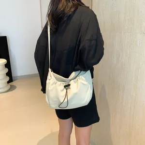 Beige crescent crossbody bag with black drawstring closure and minimalist slouchy design
