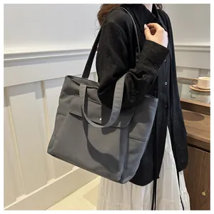 Détail latéral d'un grand sac cabas en toile gris foncé avec poche avant à boucle