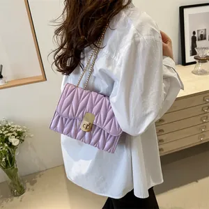 Détail d'un sac à main matelassé lilas avec plis verticaux et bandoulière en chaîne dorée