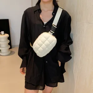 Détail du sac banane matelassé crème avec bandoulière large sur modèle en noir