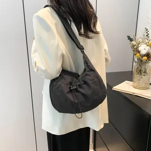 Detail of minimalist black nylon crossbody bag with drawstring and adjustable strap