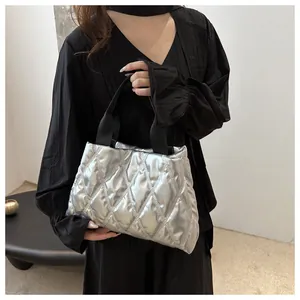 Detail of silver metallic quilted tote bag with diamond stitching and black fabric handles