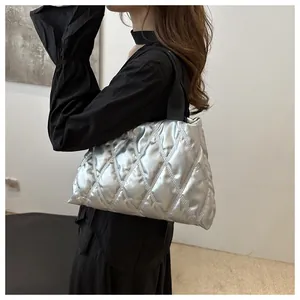 Close-up of silver quilted tote bag with large diamond stitching and black straps