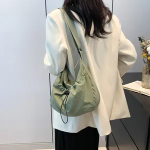 Close-up of grass green cloud bag with drawstring closure and wide shoulder strap