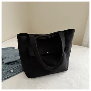 Détail du sac cabas en toile noire avec bouton-pression argenté et poche avant pratique