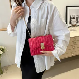 Sac bandoulière matelassé rose rouge avec chaîne dorée et fermoir pivotant sur modèle