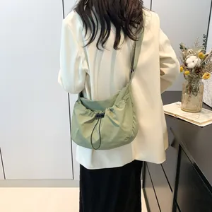 Detail of light green crescent shoulder bag with drawstring pleats on female model