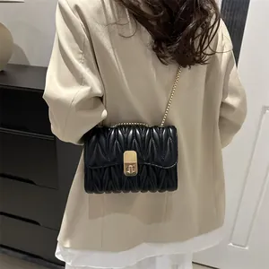 Détail d'un sac bandoulière en cuir matelassé noir avec une élégante chaîne dorée