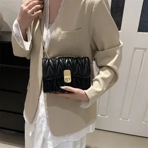 Détail d'un sac bandoulière matelassé noir avec chaîne dorée et fermoir pivotant
