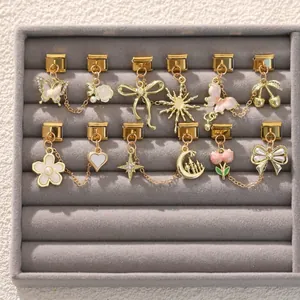 Dettaglio di ciondoli italiani dorati con fiori smaltati e perle su vassoio in velluto