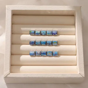 Macro shot of 15 nautical enamel charms for Italian bracelets in a cream jewelry box
