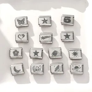 Macro detail of modular Italian charm links in polished steel with diverse engraved symbols