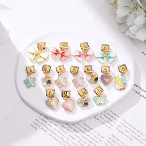 Lot détaillé de 15 breloques en émail doré avec motifs de cœur, de fleur et de papillon