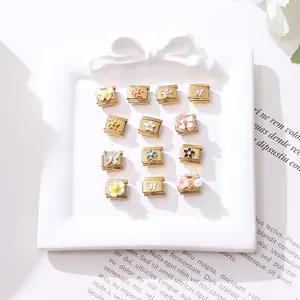 Detailaufnahme von 12 goldenen Edelstahl Italian Charms mit Emaille-Blumen- und Schmetterlingsdekor
