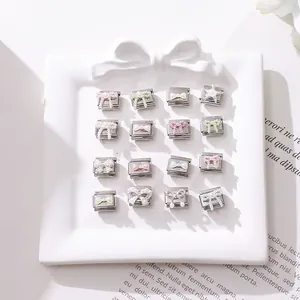Macro shot of 16 macaron-colored butterfly and star charms on a white ceramic tray