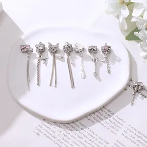 Detailed set of silver charms with pink stones and pearls on a white ceramic tray