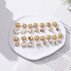 Macro shot of gold Italian charm beads with colorful resin motifs on a ceramic tray