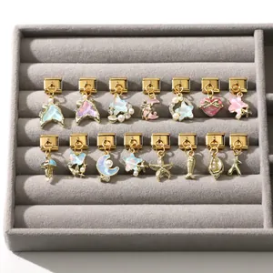 Makroaufnahme von 15 goldenen italienischen Charms mit irisierenden Stern- und Meeresmotiven